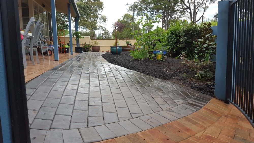 A Brick Walkway Leading To A House With A Fence — Green Envy Landscape & Garden Services In Cameron Park NSW