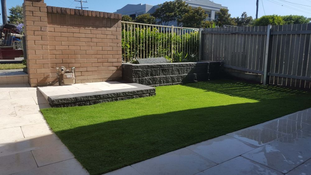 A Lawn With A Brick Wall And A Fence In The Background — Green Envy Landscape & Garden Services In Cameron Park NSW