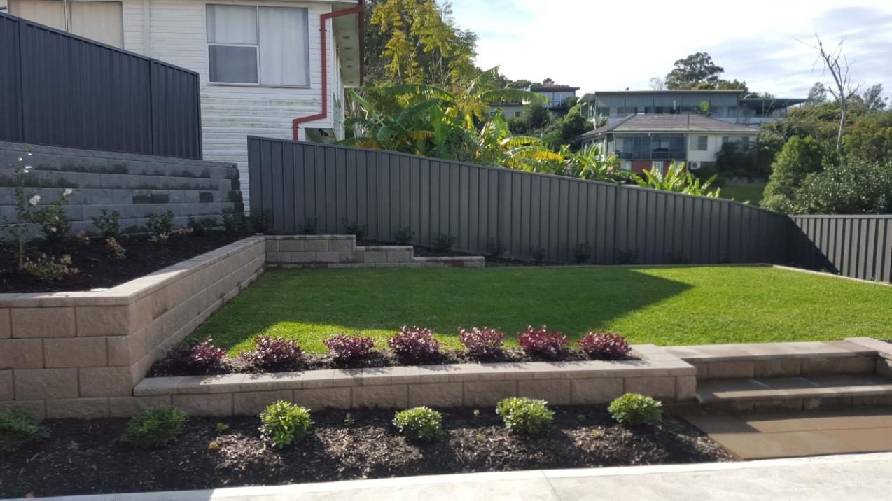 Landscaped Backyard With Retaining Walls, Green Grass, and Dark Gray Fence — Green Envy Landscape & Garden Services In Cameron Park NSW