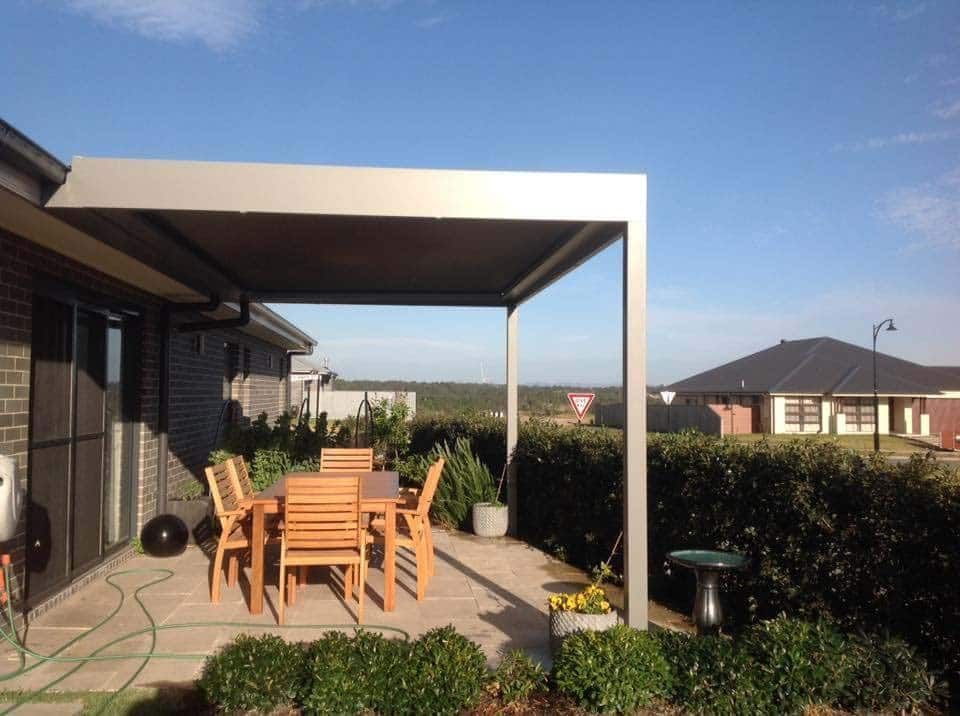 Outdoor Patio With a Wooden Table and Chairs Under a Grey Awning — Green Envy Landscape & Garden Services In Cameron Park NSW