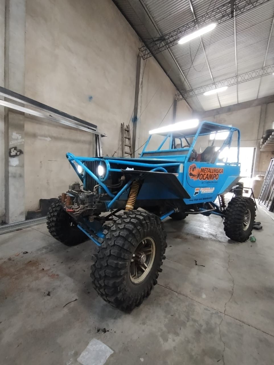 Buggy todoterreno azul con neumáticos grandes en un garaje.