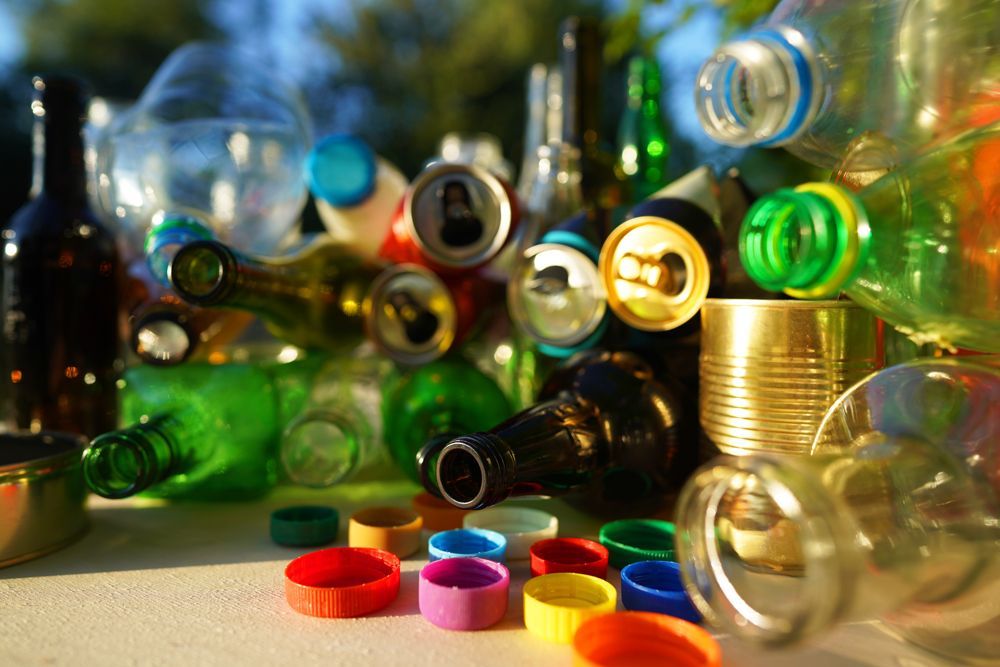 A pile of bottles , cans , and lids on a table.