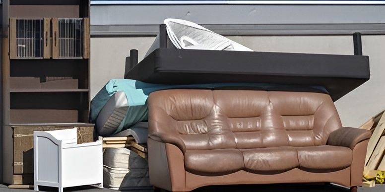 A brown leather couch is sitting on top of a pile of furniture.