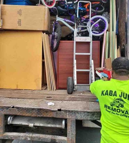 A man in a neon green shirt is standing in front of a moving truck.