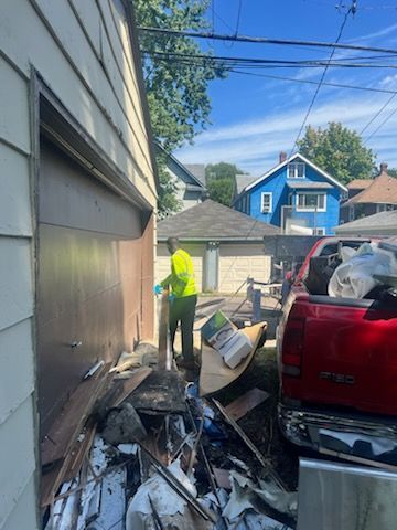 A man is standing in front of a garage filled with trash.