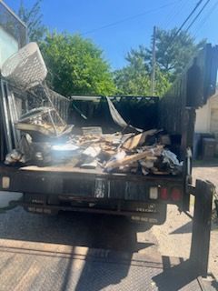 A dump truck filled with junk is parked in a driveway.