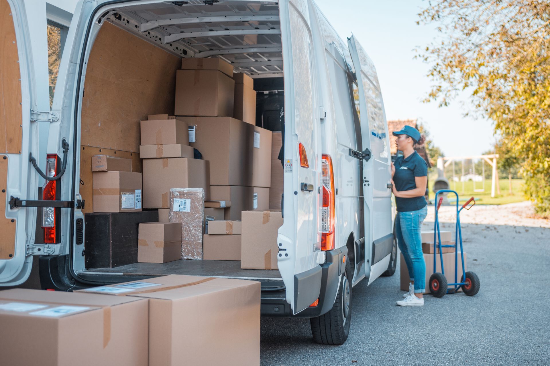 A delivery woman is loading boxes into a van