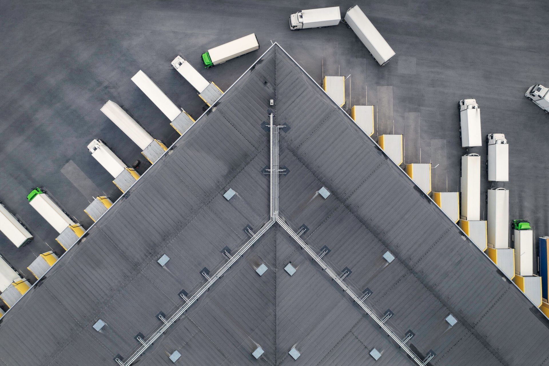 An aerial view of a warehouse with trucks parked on the roof.