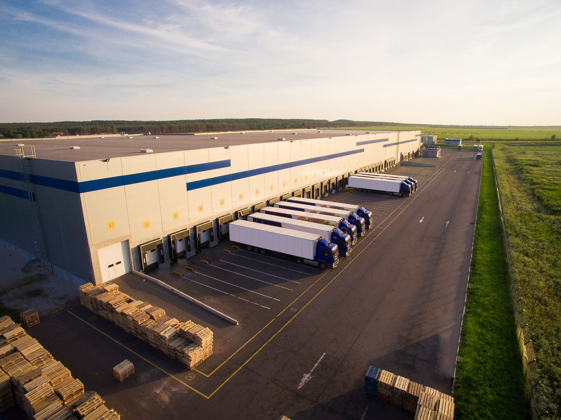 An aerial view of a large warehouse with trucks parked in front of it.