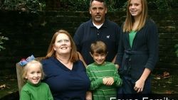 A family is posing for a picture together in front of a brick wall.