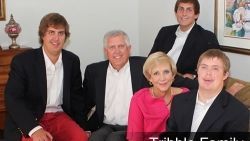 A family is posing for a picture while sitting on a couch.