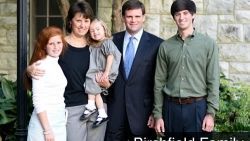 A family posing for a picture in front of a brick building.