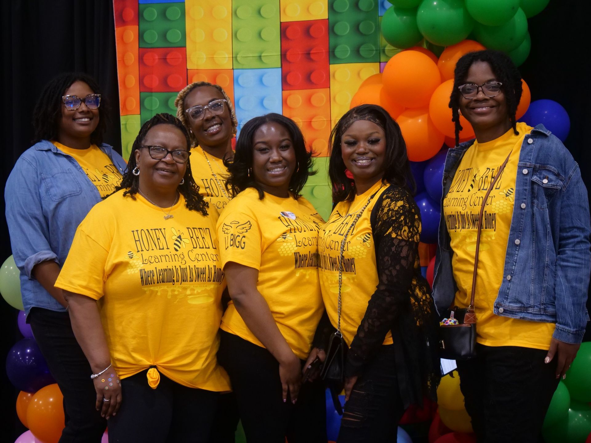 A group of women are posing for a picture in front of a lego wall.