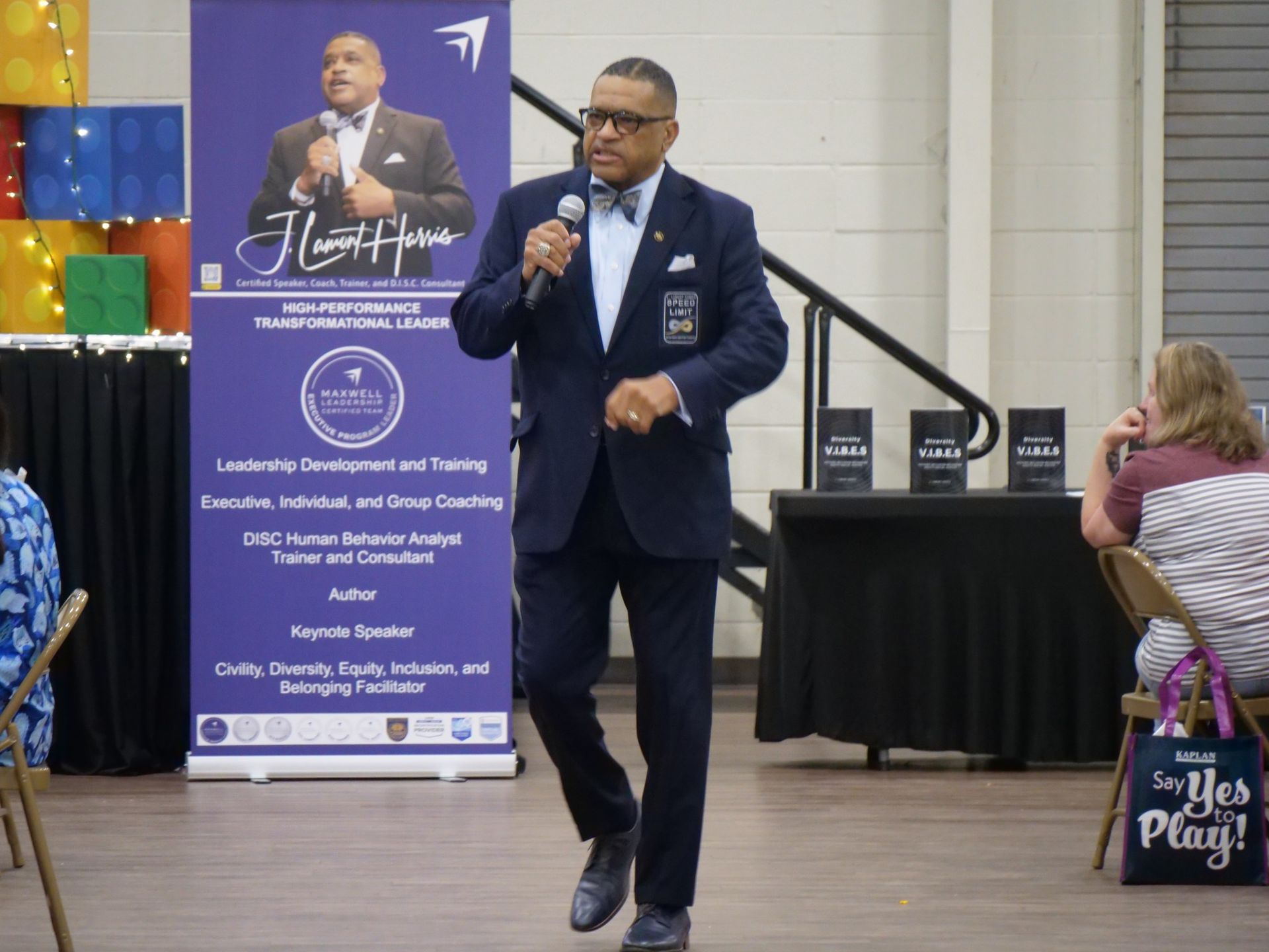 A man in a suit and bow tie is speaking into a microphone.