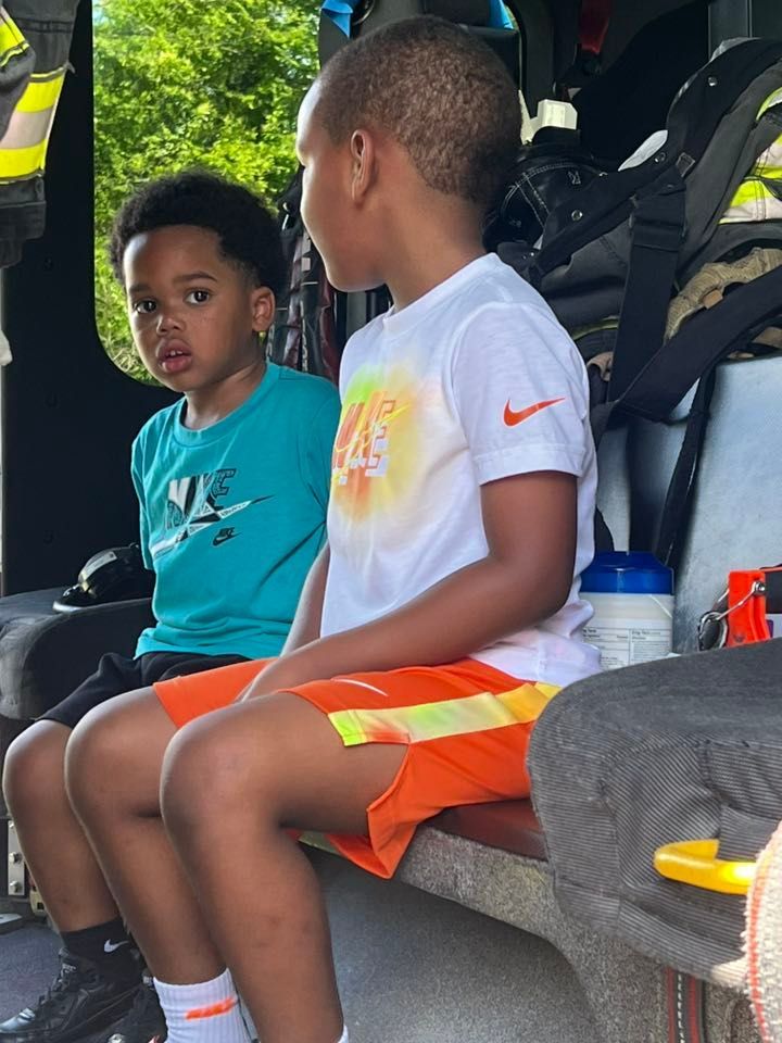 Two young boys are sitting in the back of a fire truck.