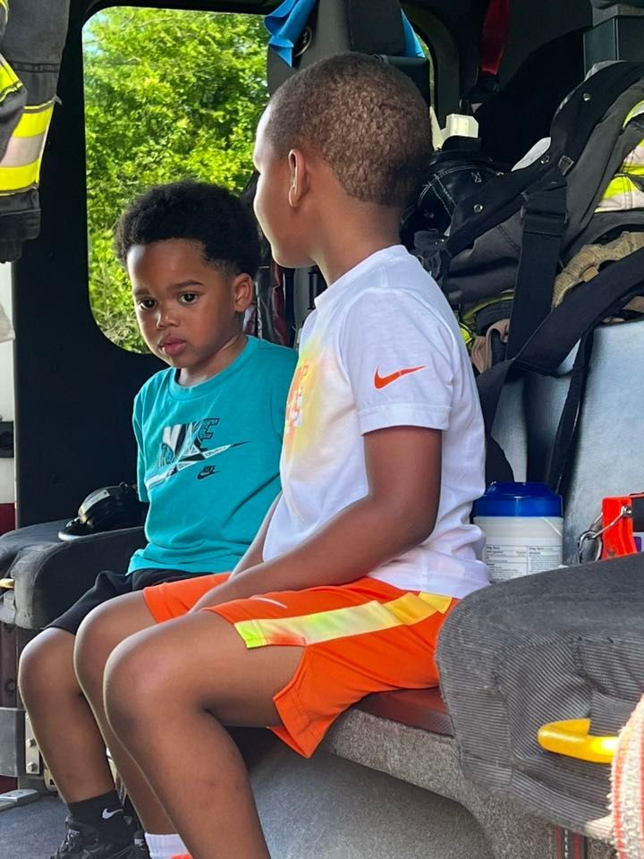 Two young boys are sitting in the back of a fire truck.