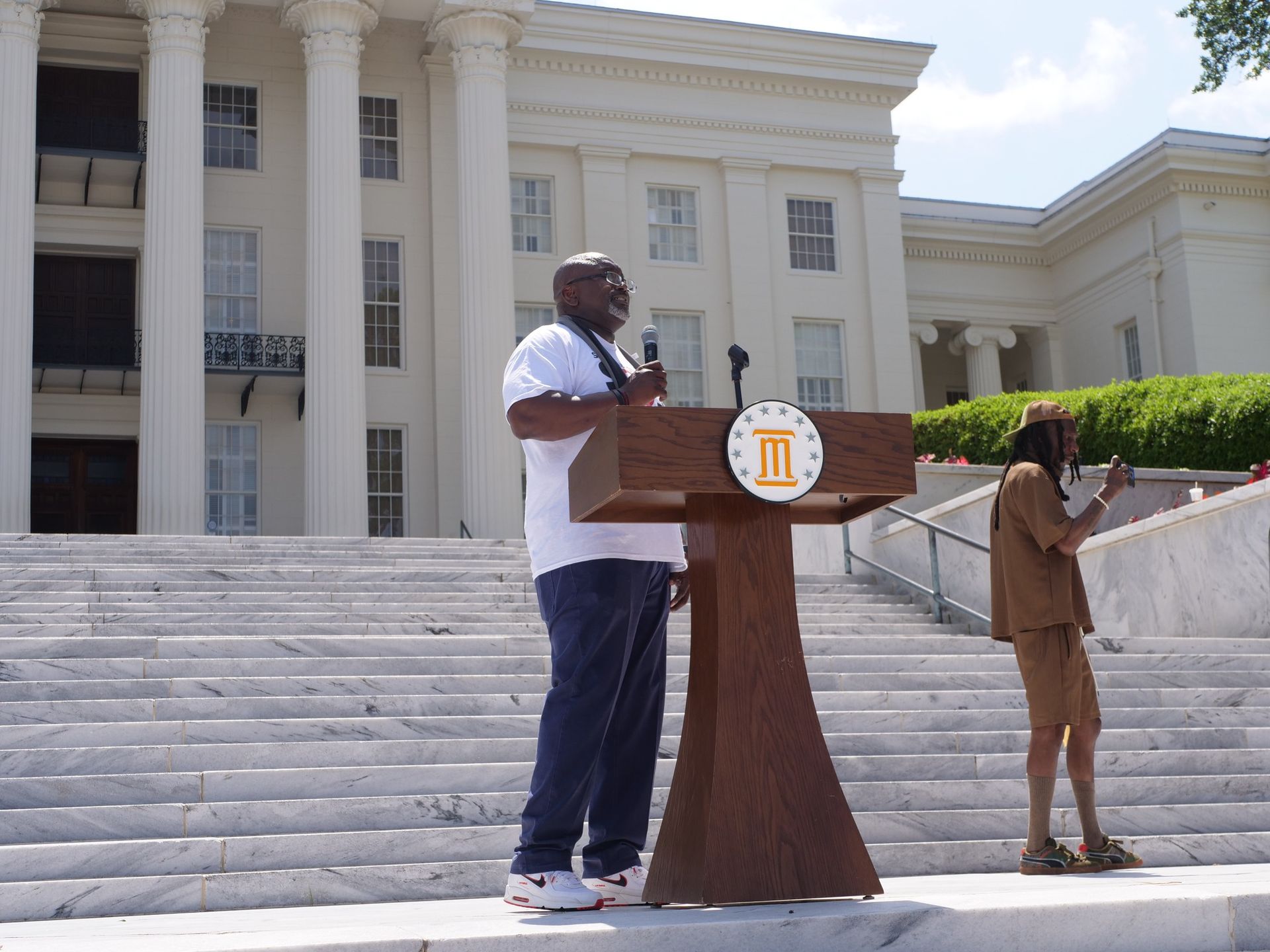A man stands behind a podium with the letter i on it