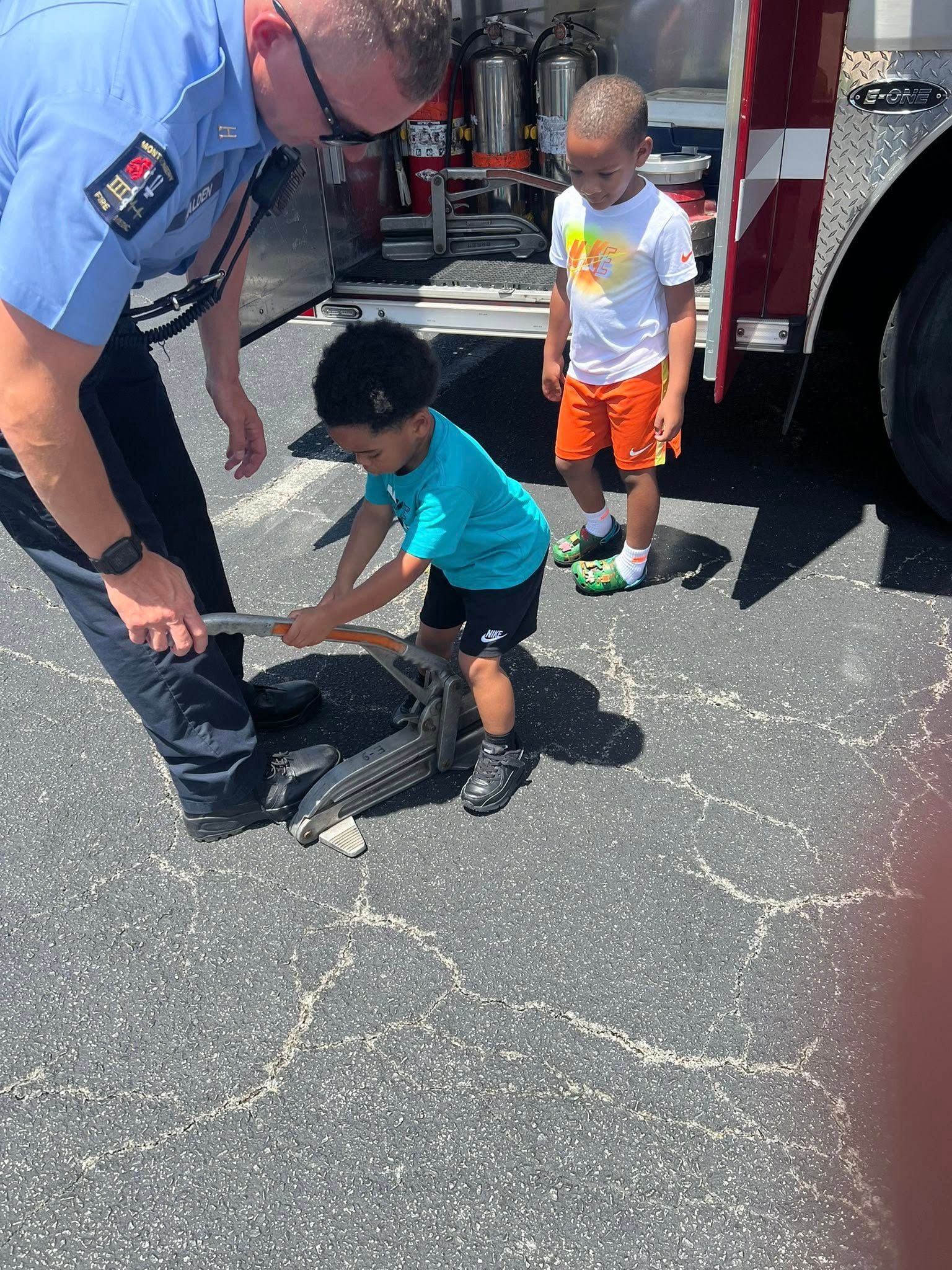 Two young boys are playing with a fire hose in front of a fire truck.