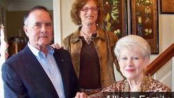 A man and two women are standing next to each other in a room.