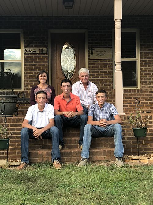 A family is sitting on the steps of a brick house.