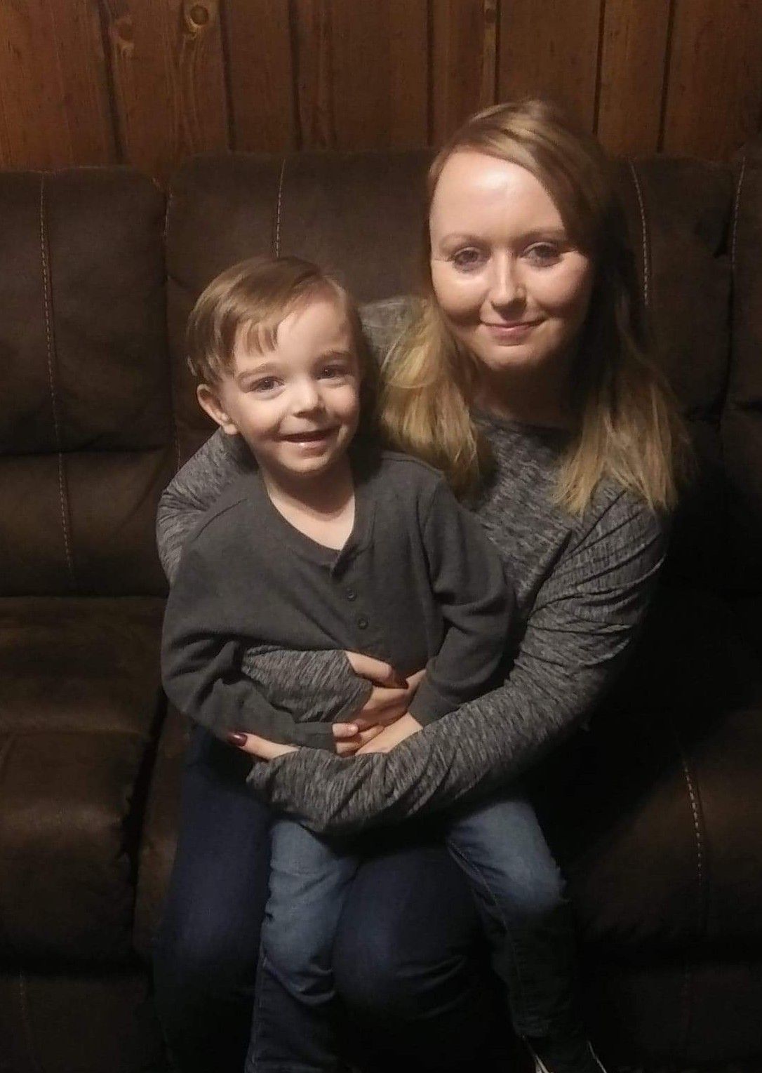 A woman is sitting on a couch holding a little boy.