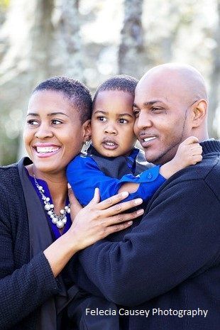A man and woman are holding a little boy in their arms.