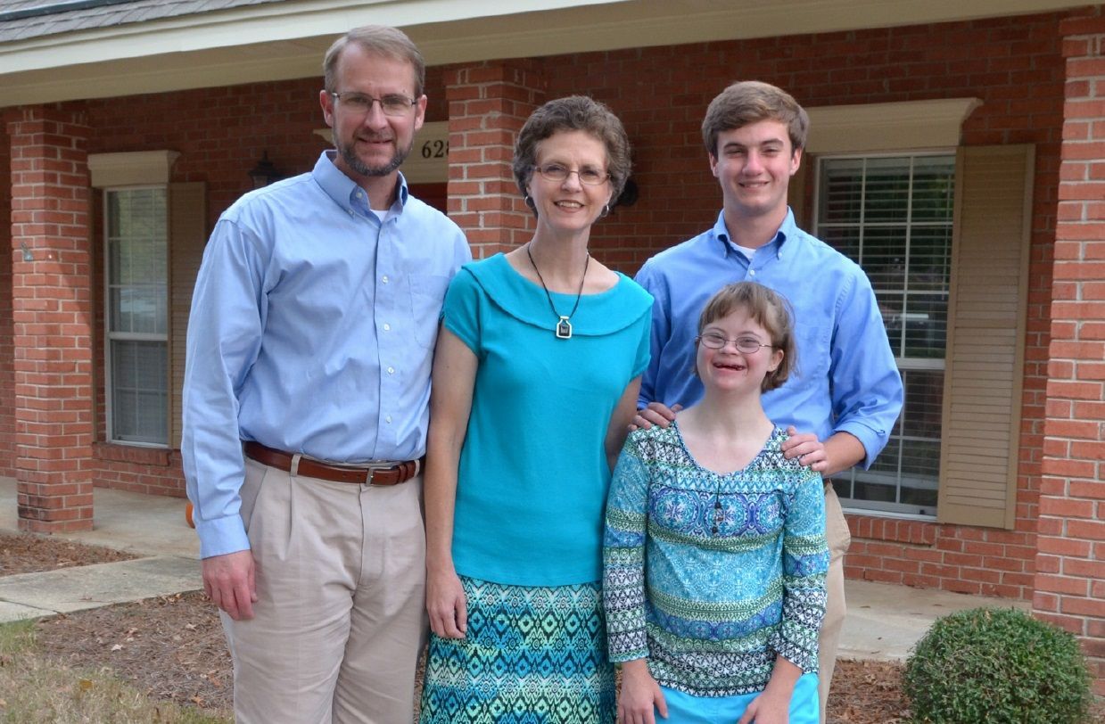 A family posing for a picture in front of a brick house