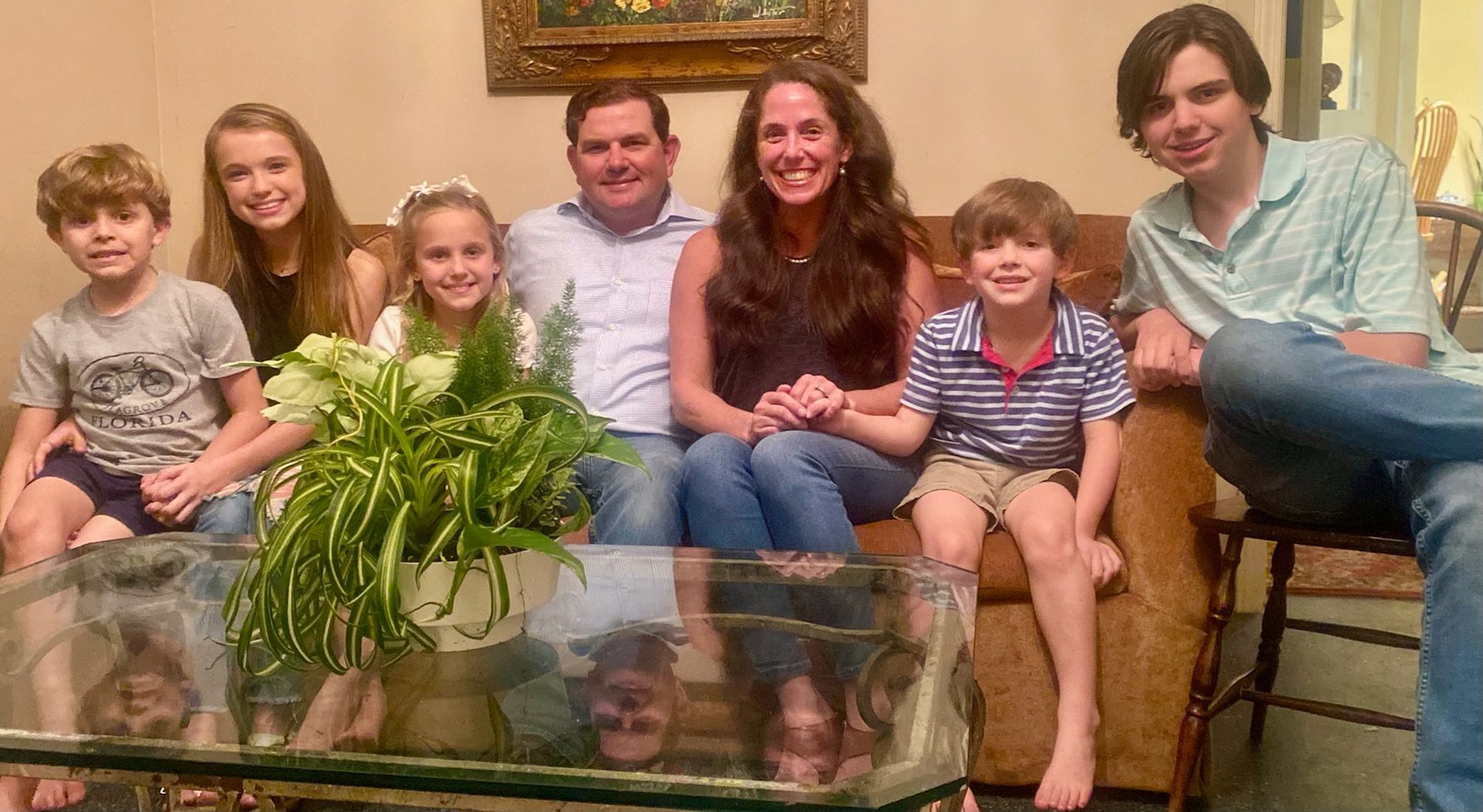 A family is posing for a picture while sitting on a couch in a living room.