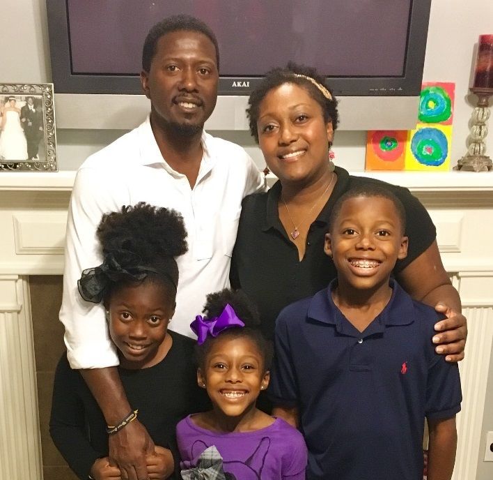 A family posing for a picture in front of a flat screen tv