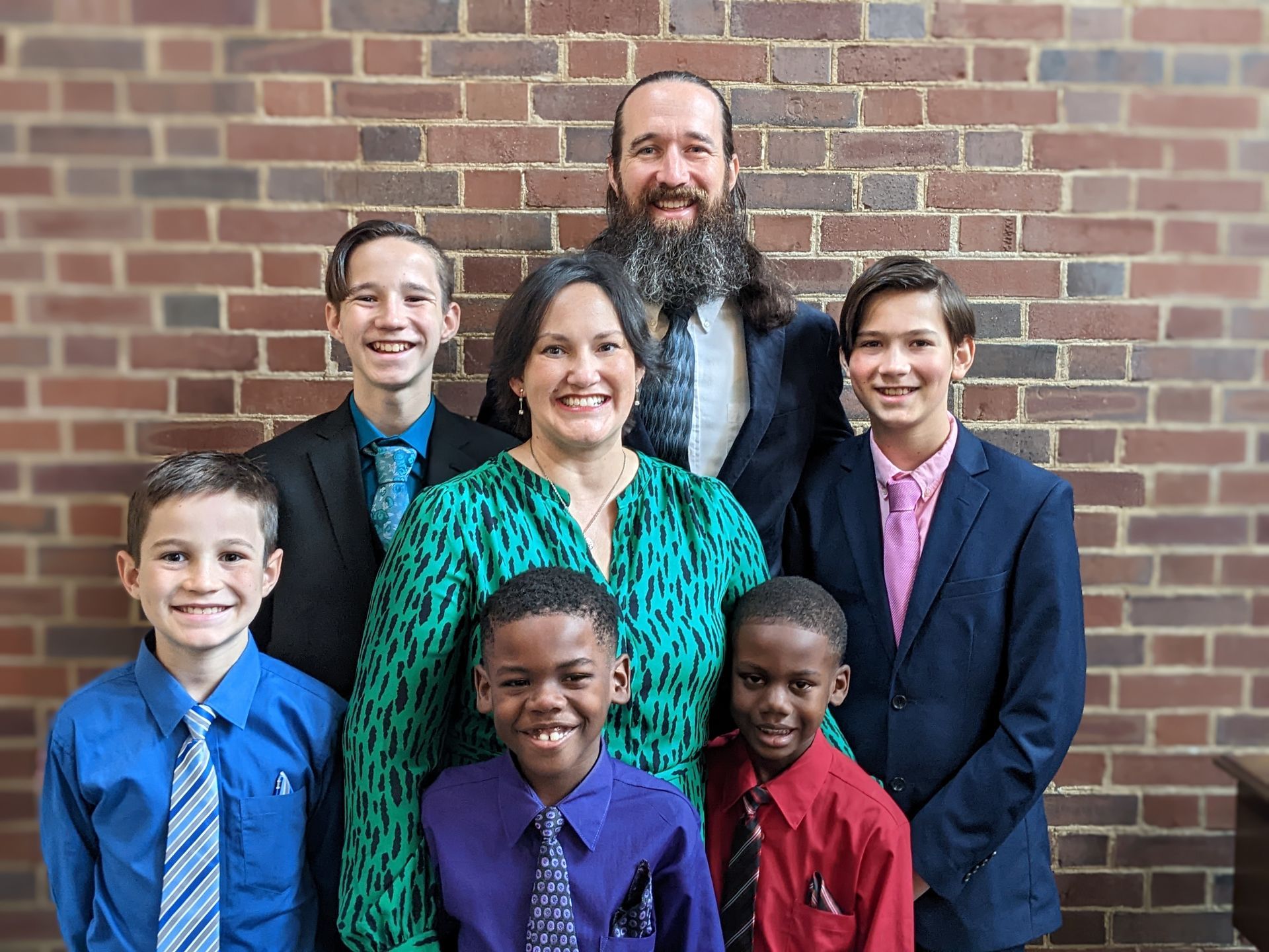 A family is posing for a picture in front of a wooden building.
