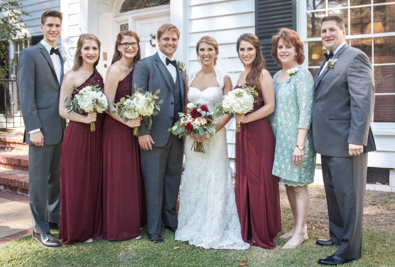 A bride and groom are posing for a picture with their wedding party.