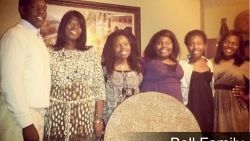 A group of people are posing for a picture together in a living room.