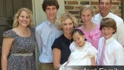 A family posing for a picture in front of a brick building.