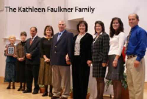A group of people standing in front of a sign that says the kathleen faulkner family