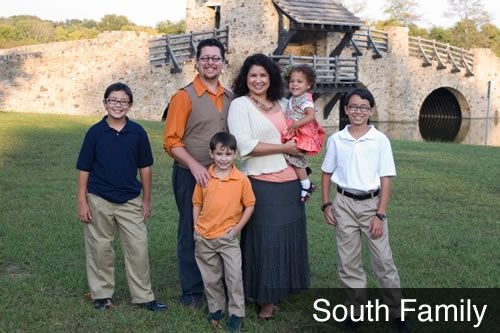 A family poses for a picture in front of a stone wall.