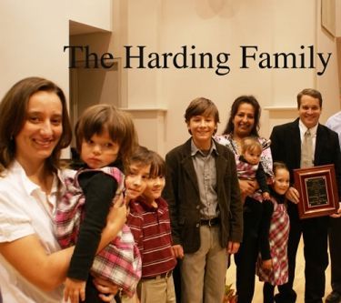 A group of people standing in front of a sign that says the harding family