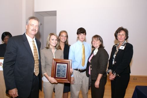 A group of people standing around a man holding a plaque