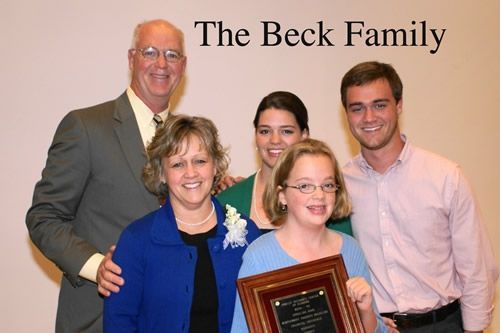 The beck family posing for a picture with a plaque