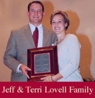 A man and a woman holding a framed plaque that says jeff & terri lovell family