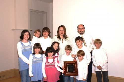 A family posing for a picture while holding a plaque
