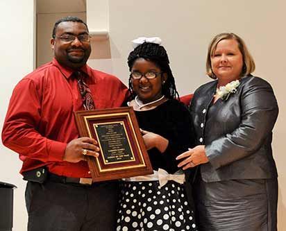 A man and two women are standing next to each other holding a plaque.