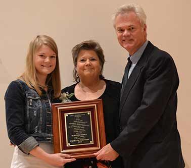 Three people are standing next to each other holding a framed plaque.