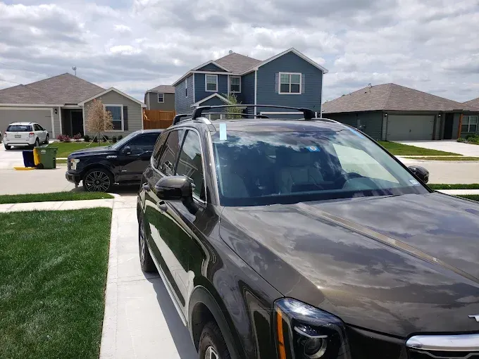 SUV parked in driveway, houses in background, sunny day.