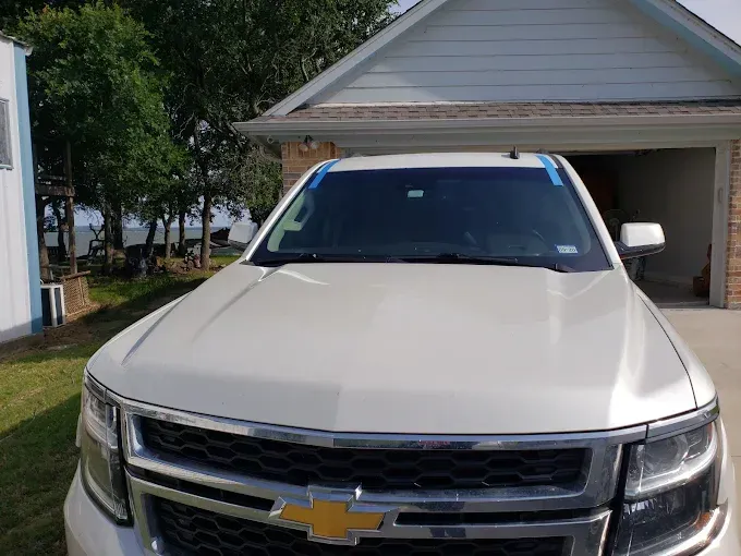 White SUV parked in front of a garage, blue tape on windshield.