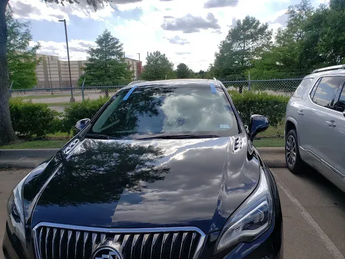 Black Buick SUV parked, with a silver SUV to the right, in an outdoor parking area on a sunny day.