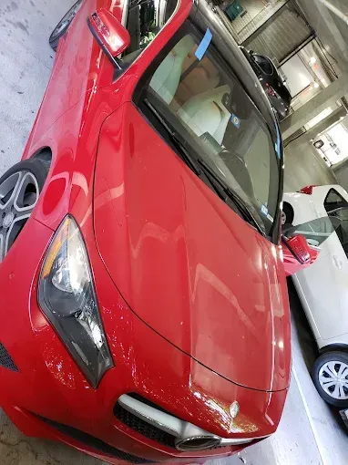 Red sports car in a garage, next to a white car.