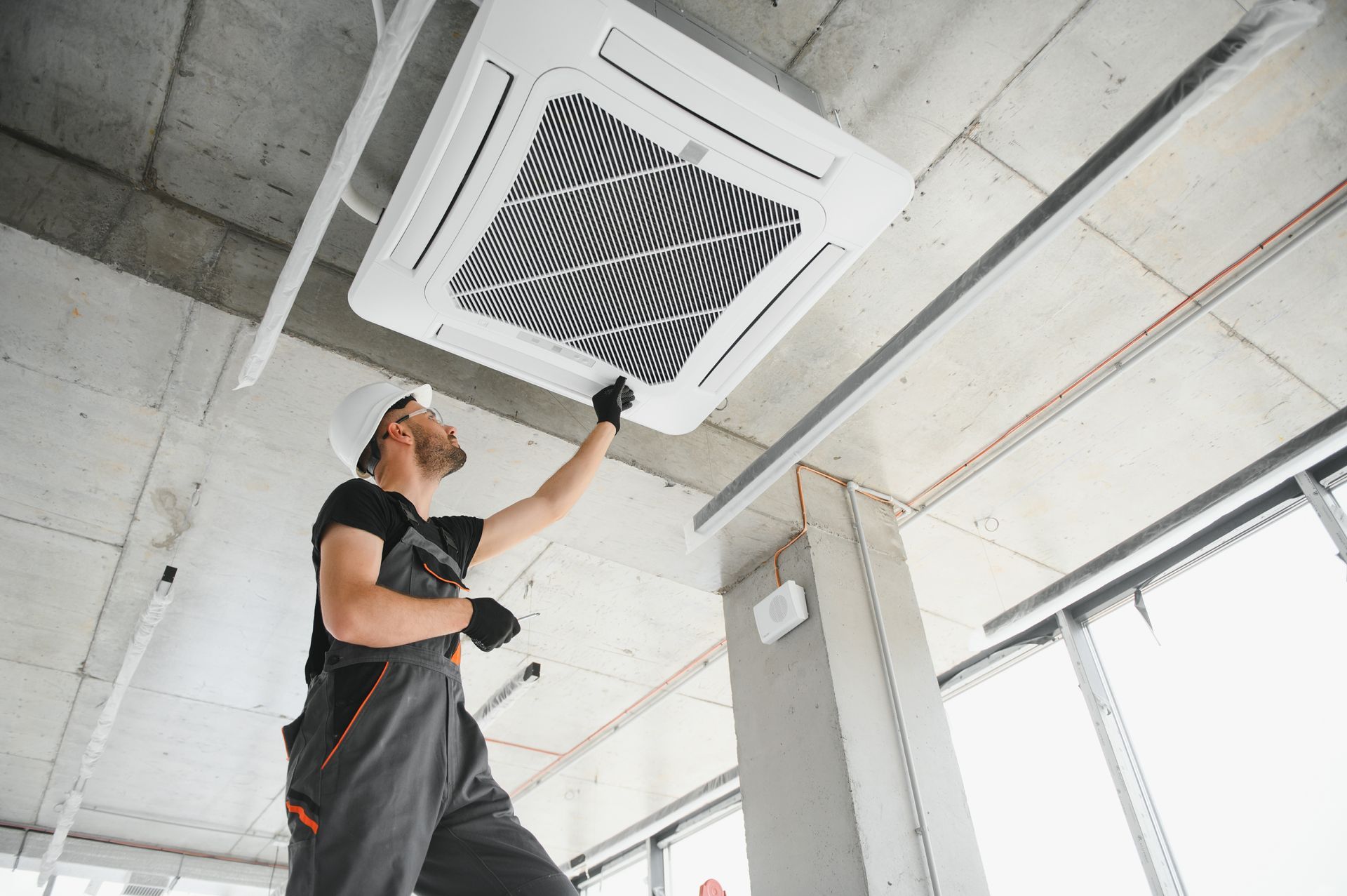 Un uomo sta lavorando su un climatizzatore da soffitto in un edificio.
