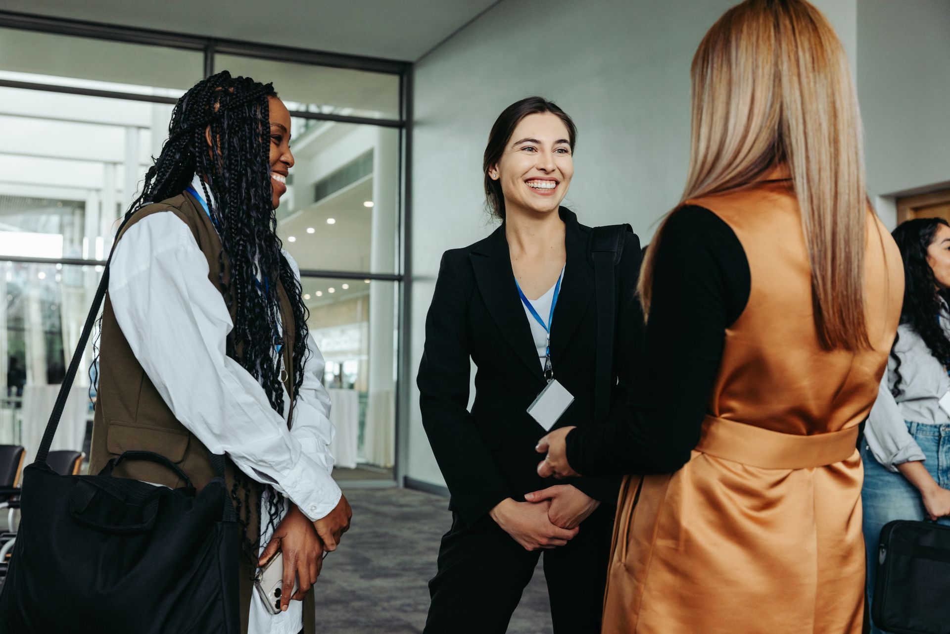 A group of women are standing in a hallway talking to each other.