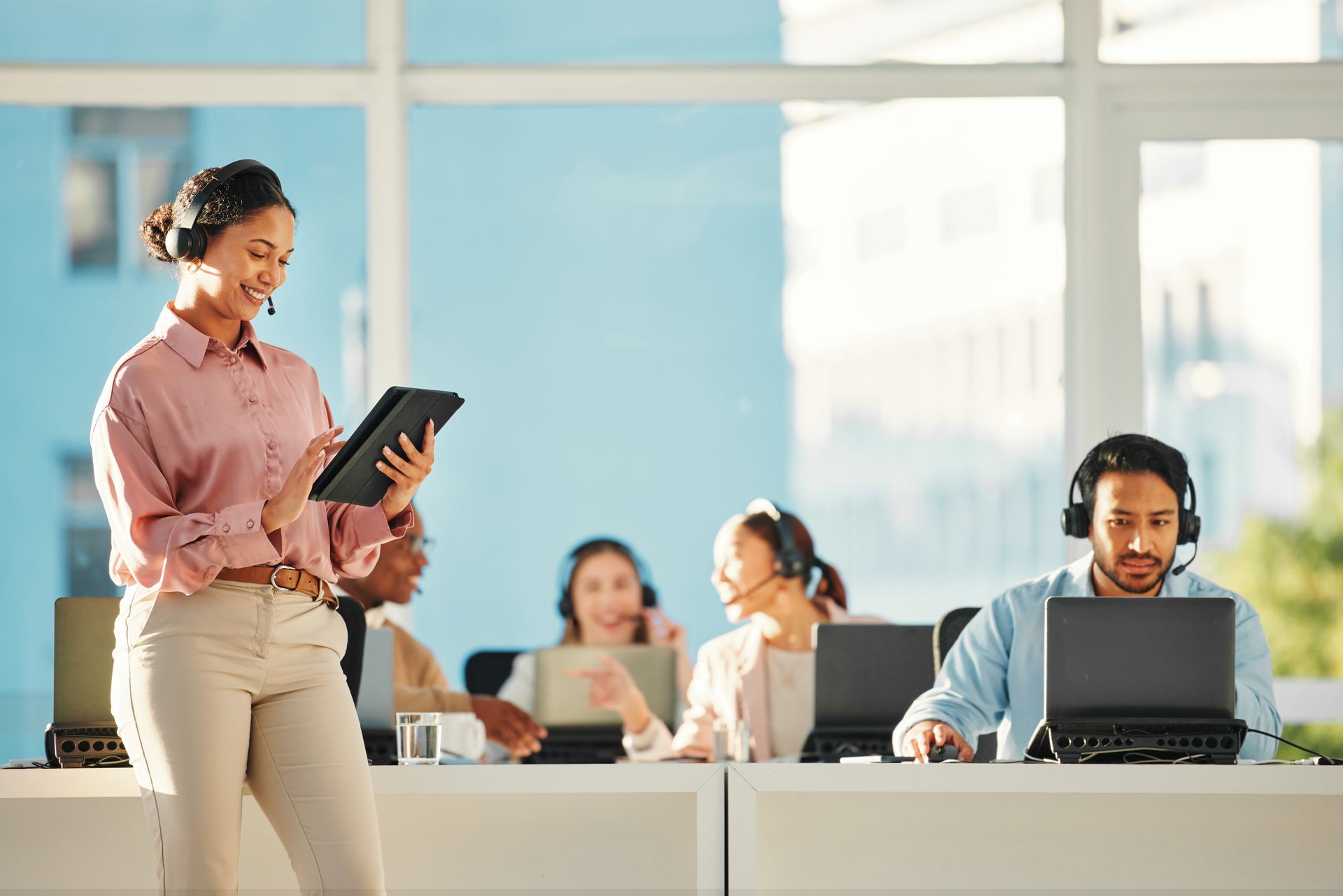 A woman is standing in front of a group of people using laptops in an office.