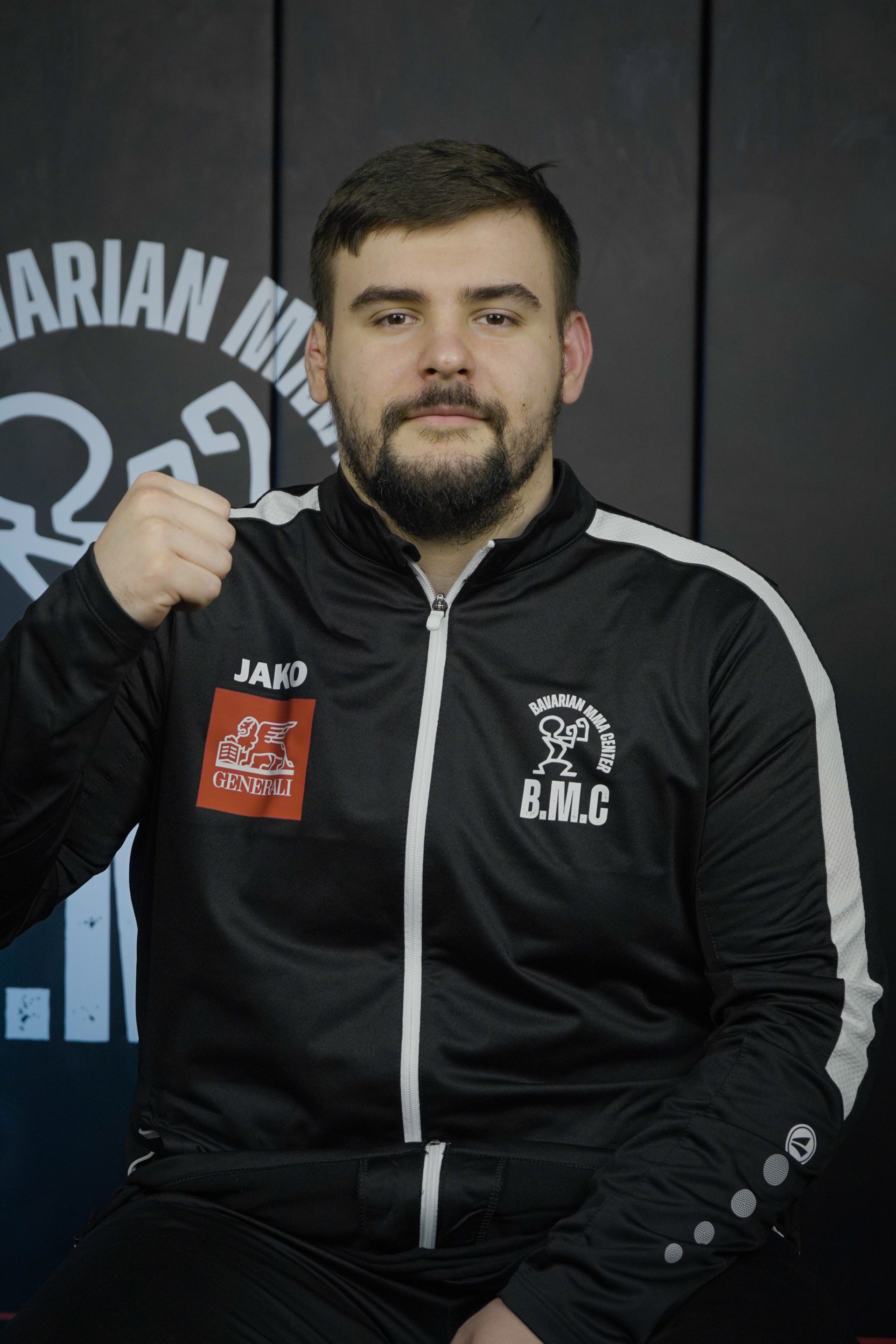 Ein Mann in schwarzem T-Shirt steht vor einer Turnhallenkulisse.